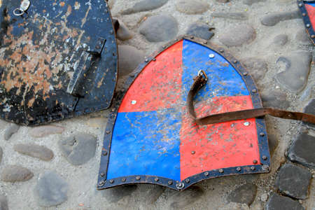 metal medieval shields and leather strap on paved roadの写真素材