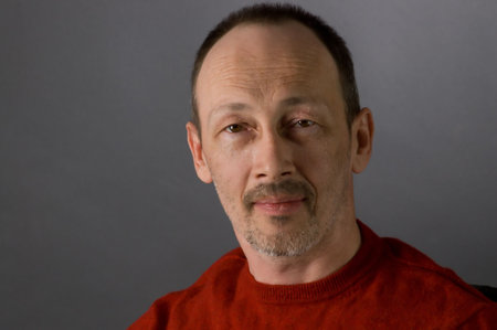 The man in a red sweater sits on a chairの写真素材