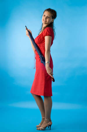 The girl in a red dress on a dark blue background with a umbrellaの写真素材