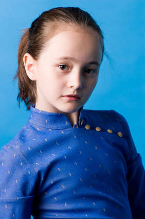 The girl of ten years in studio on a dark blue background, in the chinese dress.の写真素材