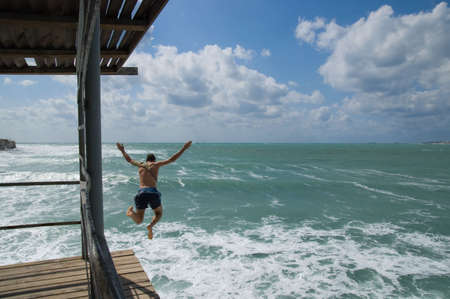 The guy jumps from a mooring in emerald waves.の写真素材