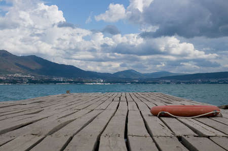 A wooden mooring with a life-buoy ring in seaside small town.の写真素材