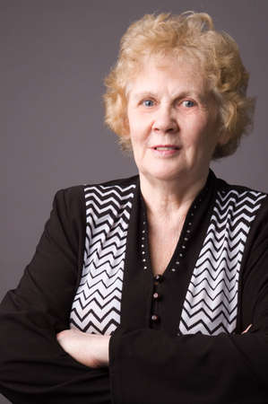 The elderly woman in a black dress on a grey background.の写真素材