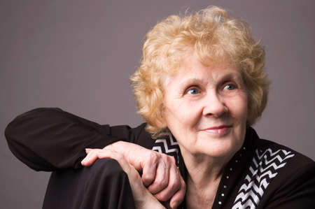 The elderly woman in a black dress on a grey background.の写真素材