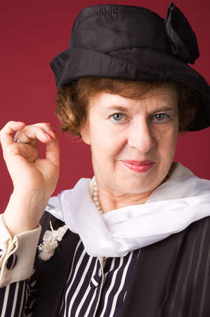 The elderly woman in a hat on a red background.の写真素材