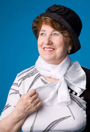 The cheerful elderly woman in a white dress on a blue background.の写真素材