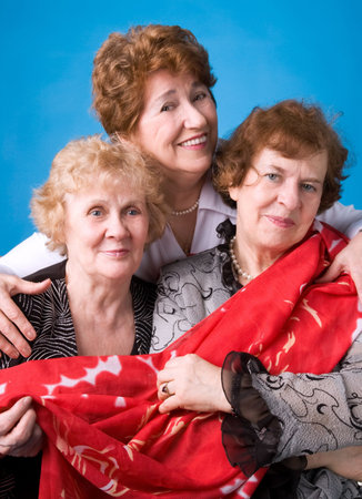 A portrait of three cheerful elderly women on a dark blue background.