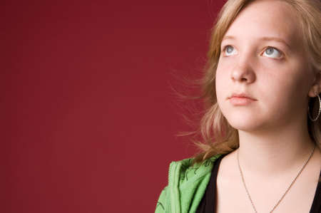 The young girl in green clothes on a red background.の写真素材