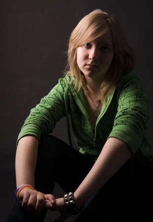 The young girl in green clothes on a black background.の写真素材