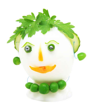 Egg garnished with parsley, cucumber, carrots and green peas on white backgroundの写真素材