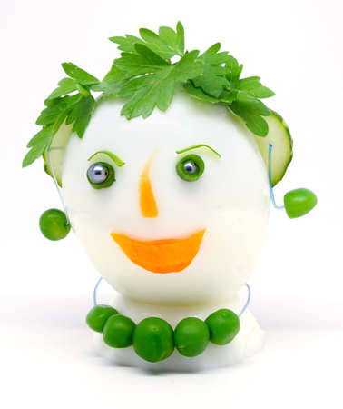 Egg garnished with parsley, cucumber, carrots and green peas on white background.の写真素材