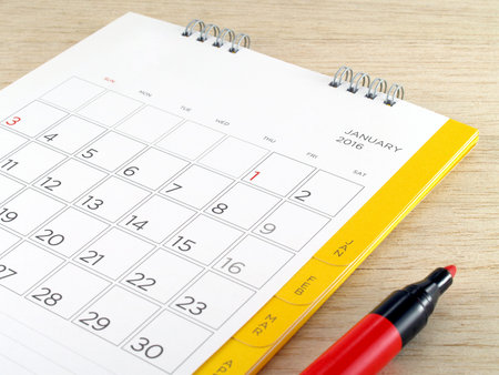 calendar with red marker pen on wooden table background