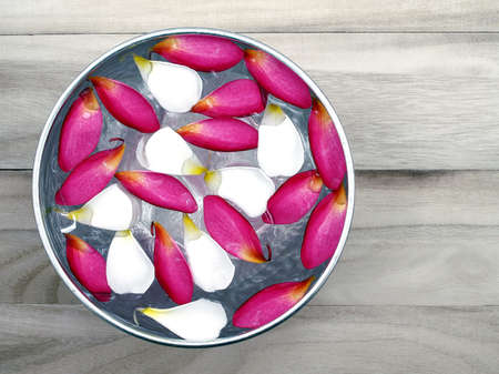 Flower petals floating in silver bowl on wooden floor background, for Songkran festival in Thailandの写真素材