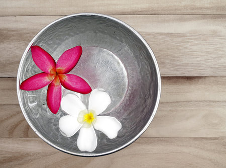 red and white flowers floating in silver bowl on wooden floor background, for Songkran festival in Thailandの写真素材
