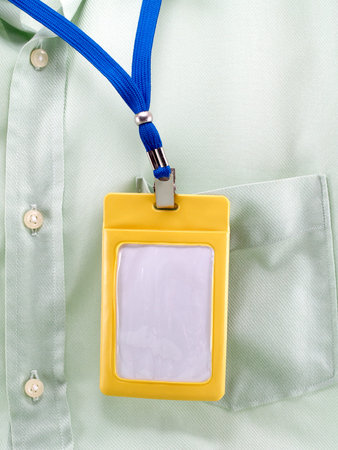yellow plastic case of neck label hanging on green shirt pocket,  blank label for your simple text