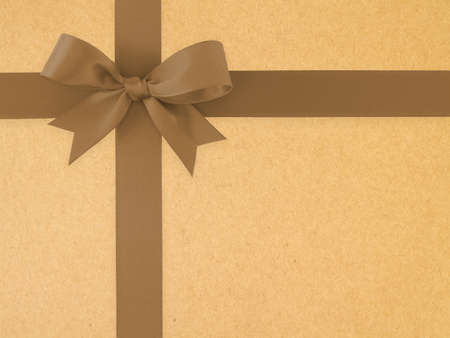 dark brown ribbon with bow on brown paper texture background, simple earth tone color decoration for gift box and greeting card, close up top viewの写真素材