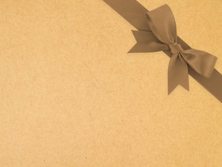 dark brown ribbon with bow on brown paper texture background, simple earth tone color decoration for add beauty to gift box, flat lay close up top view with copy spaceの写真素材