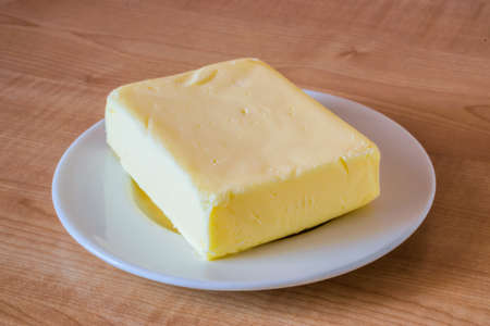 Butter on a white plate on a wooden table.の写真素材
