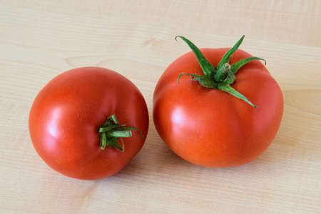 Two fresh tomatoes on wooden table. Healthy food.の写真素材