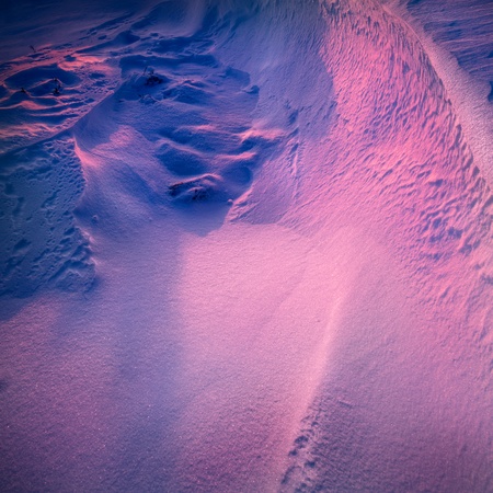 As the sun sets the low angle light casts colour temperature shadows over drifted snow, where the light strikes the snow it turns pink, and shadows aquire a blue colour cast. This naturally occuring mixed lighting helps to emphasize the textures of the wiの写真素材