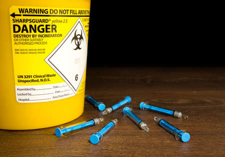 Needles laying next to a sharps binのeditorial素材