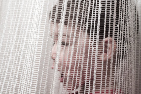 Boy behind a white curtain