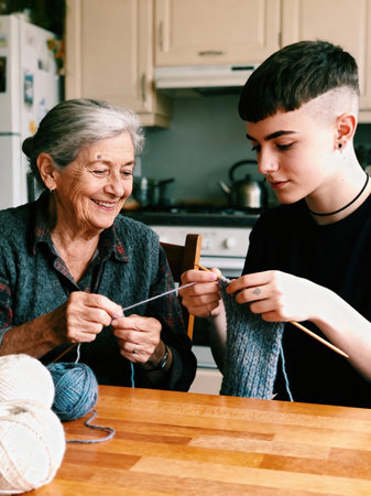 An elderly woman and a younger person kneel together at a kitchen table, sharing a creative hobby and warm interaction.の素材