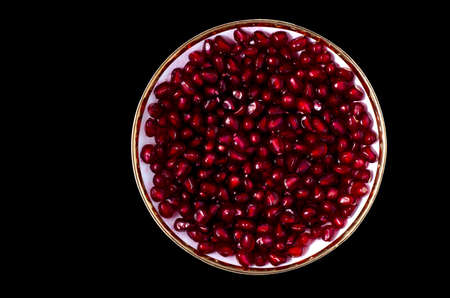 saucer with pomegranate seeds on a black backgroundの写真素材