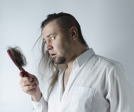 a man looking at a hairbrush with a loosing hairの写真素材