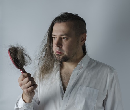a man looking at a hairbrush with a loosing hairの写真素材