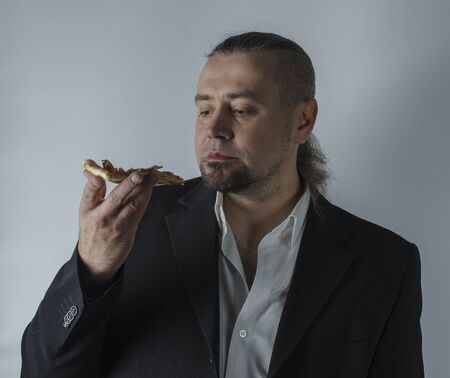 a man in a jacket eating a slice of pizzaの写真素材