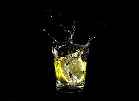 lemon splashing in glass isolated on a black backgroundの写真素材
