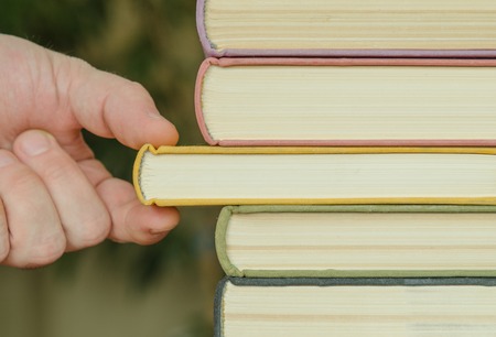 hand of man or woman takes a book on a shalf in the room or libraryの写真素材