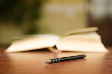 pen on background of a stack of colorful books in a library or a roomの写真素材