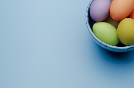 colored easter eggs on a saucer on a blue backgroundの写真素材