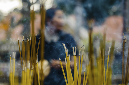 Burning yellow incense sticks in a pot. Aromatic sticks and smoke in a Buddhist temple in Cambodiaの写真素材