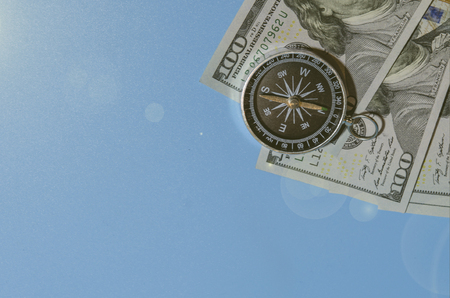 compass on pile of dollar bills usning as travel concept or world economics fortune direction.の写真素材