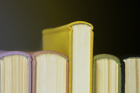 A stack of colorful books. Education, knowledge, learn, study and wisdom concept. Horizontal layout of childrens books. Front of books with colorful covers.の写真素材