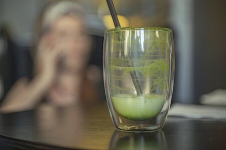 after drink concept close up. an empty cup of soft drink is matcha. green tea late on wooden table against girl.の写真素材