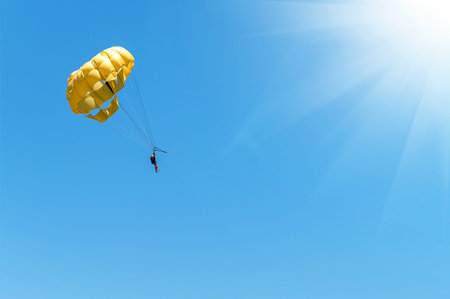 Skydiver flying with a yellow parachute by speed boat on sea. Skydiver control parachute down on...