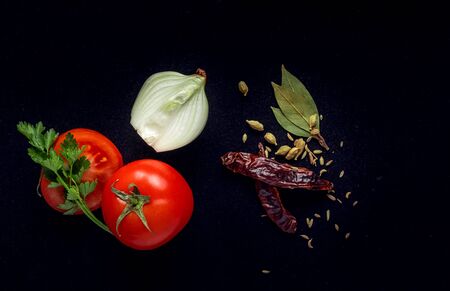 tomatoes, onions and spices on a black backgroundの写真素材
