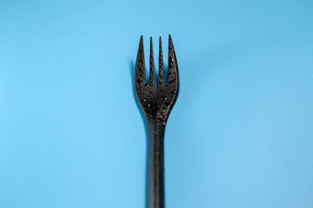 Black plastic fork on a blue backgroundの写真素材