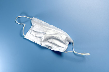 White medical mask on blue background. Old Medical mask protection against pollution, virus, flu,...