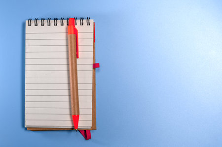 Notepad with eco pen on blue background. Sketchbook made of craft paper and a pen