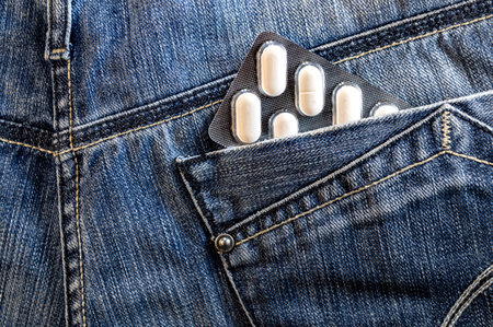 Pills in jeans pocket. Blister pack of white pills in back jeans pocket. Care health conceptの写真素材