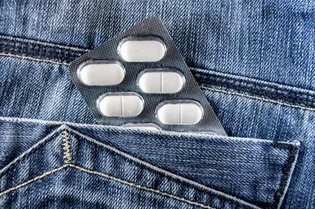Pills in jeans pocket. Blister pack of white pills in back jeans pocket. Care health conceptの写真素材