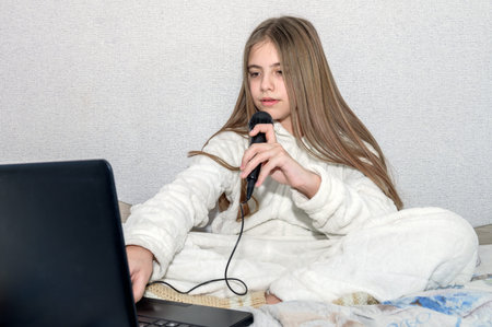 Girl learning to sing online. Girl sings into a microphone and shoots a video blog on a laptop....