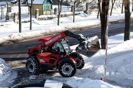 RIVNE, UKRAINE - FABRUARY 16, 2021. Removing snow from the streets with a tractor. A bulldozer with...