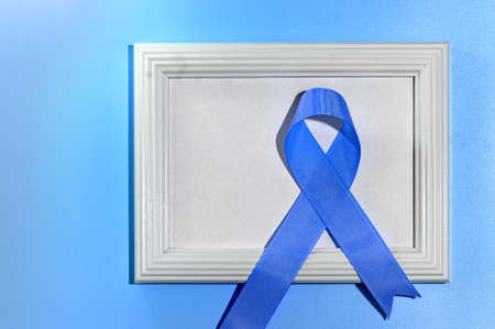 Blue ribbon with white frame on blue background with copy space. Colorectal Cancer Awareness. Colon cancer of older person. World diabetes day.の写真素材