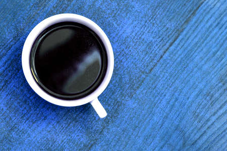 White cup of coffee on a blue table. View from aboveの写真素材
